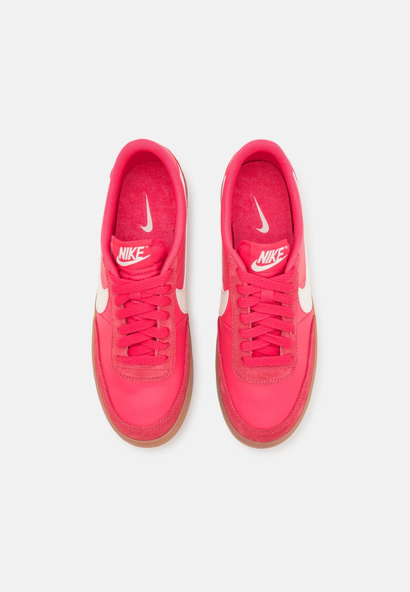 Zapatillas Nike de color rosa brillante con un upper de cuero suave, detalles en blanco y cordones redondos. Cuenta con una suela de goma texturizada.