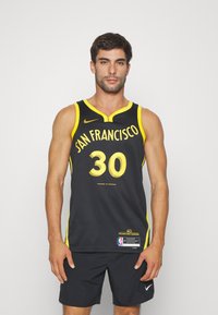 Camiseta de baloncesto negra con detalles en amarillo. En el frente presenta el texto "SAN FRANCISCO" y el número "30". Logotipo de Nike y etiqueta de la NBA en la parte inferior.