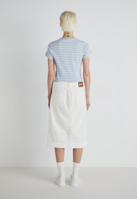 Stripete lyseblå t-skjorte og hvit denimskjørt med baklommer. Hvite sneakers og ankellange sokker. Minimalistisk design, ingen synlige mønstre.