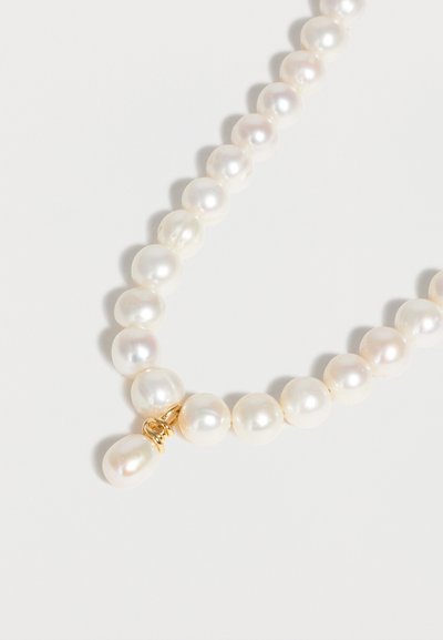 Γιρλάντα από λευκές στρογγυλές πέρλες με ένα οβάλ μενταγιόν πέρλας τυλιγμένο σε χρυσό σύρμα σε λευκό φόντο.