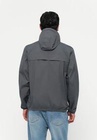 Chaqueta con capucha gris de textura suave, con un detalle de solapa en la parte trasera y puños elásticos, combinada con un tejido vaquero azul claro.