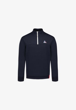 Marineblauwe pull met een kwartrits, voorzien van een witte ritssluiting en een klein logo op de borst. Glad materiaal en ribgebreide manchetten en zoom.