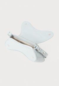 Light blue patent leather bag with a butterfly shape, smooth texture, adjustable strap, and silver hardware accents. Zippered closure.