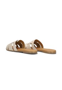 Beige leren slippers met meerdere overlappende banden en een platte tan kleurige zool. Gladde textuur met een open rugontwerp.