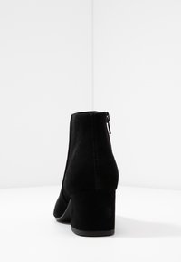 Czarne zamszowe botki za kostkę z średnim obcasem typu blok, zamek błyskawiczny z tyłu i gładką powierzchnią. Prosty, elegancki design.