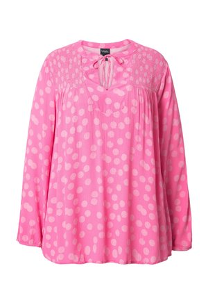 Lyserød bluse med en tekstureret yoke, der har store hvide polka dots, en V-udskæring og lange ærmer. Fremstillet af letvægtsstof.