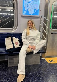 Grå sweatshirt och sweatpants-outfit, ljusbeiga stövlar, canvas tote bag med marinblå detaljer, sittande i en tunnelbanevagn med en karta i bakgrunden.