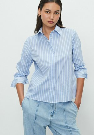 Light blue button-up shirt with white vertical stripes, long sleeves with rolled cuffs, made from a smooth woven fabric.