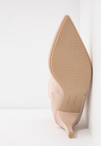 Nude szpilki z ostro zakończonym noskiem i teksturowaną gumową podeszwą. Górna część z gładkiej skóry, rozmiar 37, oznaczone "Wyprodukowano w Hiszpanii" na podeszwie.