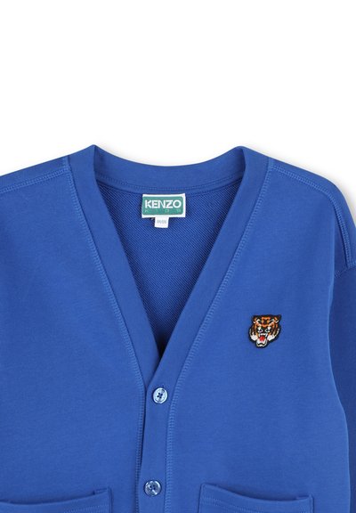 Blue cotton cardigan with a V-neckline, two front pockets, and a tiger embroidery detail. Features two buttons and a soft texture.