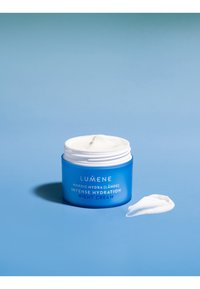 Bocal bleu de crème de nuit Lumene Intense Hydration avec couvercle blanc, mettant en valeur une texture crémeuse et une petite quantité de crème à côté sur un fond bleu.