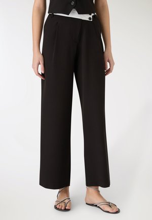 Pantaloni neri a gamba larga realizzati in tessuto liscio, con pieghe frontali, due tasche laterali e vita alta con dettagli a bottoni.