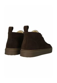 Hnědé semišové kotníkové boty s gumovou podrážkou, s jednoduchým designem na šněrování a měkkým vnitřním podšívkou. Minimální značení na patě.