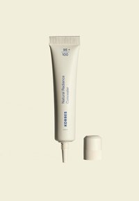 KORRES Natural Radiance Concealer in einer weißen Quetschtube mit einer spitzen Öffnung und einem passenden Schraubdeckel. Aufgedruckter Text in Blau.