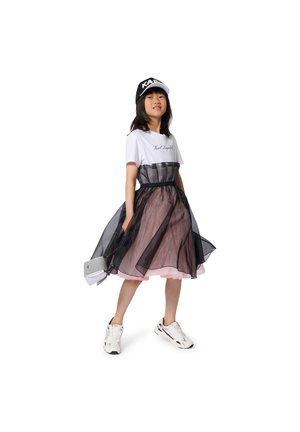 T-shirt blanc avec texte, jupe en tulle superposée noire et rose, sac argenté, baskets blanches, casquette noire avec lettrage blanc. Texture lisse.