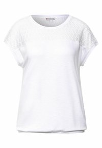 Bílé tričko s krátkými rukávy, s texturovaným krajkovým panelem na ramenou, zaobleným výstřihem a volným střihem. Měkká, hladká látka.