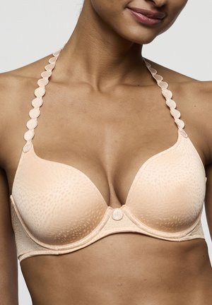 Lichtroze gevoerde beha met geaccentueerde bandjes met golvende rand, een gladde textuur en een klein knoopje in het midden tussen de cups.