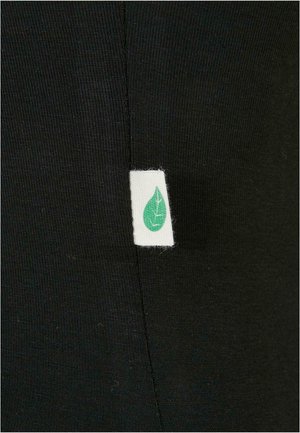 Melna auduma ar gludu tekstūru, ar baltu etiķeti, kurā ir zaļas lapas dizains, izšūta sānu šuvē.