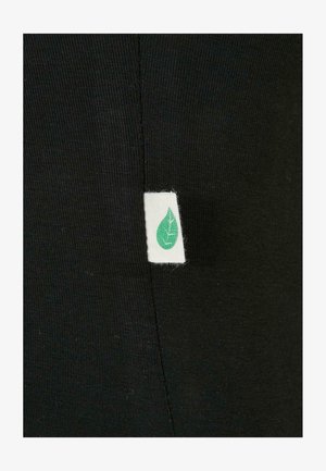 Melna auduma ar gludu tekstūru, ar baltu etiķeti, kurā ir zaļas lapas dizains, izšūta sānu šuvē.