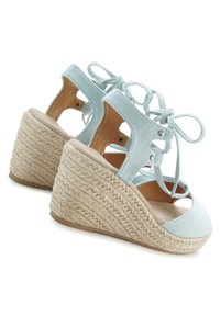 Svetlo modre espadrille platform sandale z teksturiranim pletenim peteljnjakom, odprto konico in vezanjem. Imajo izrezane stranice in svetlo rjavo podplat.