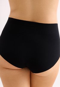 Zwarte high-waisted onderbroek van een gladde, rekbare stof, met een naadloos ontwerp dat zich aan het lichaam vormt.