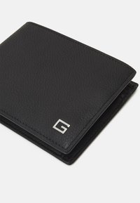Portafoglio in pelle nera con superficie testurizzata, caratterizzato da accessori in argento e un logo 'G' sulla parte anteriore. Il design pieghevole offre un'archiviazione compatta.