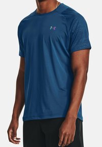 Short-sleeve athletic shirt in deep blue, featuring a subtle textured pattern and a multicolored logo on the chest. Smooth fabric.