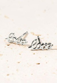 Pendientes de plata con forma de la palabra "amor", con un diseño en cursiva, bordes redondeados y un acabado pulido.