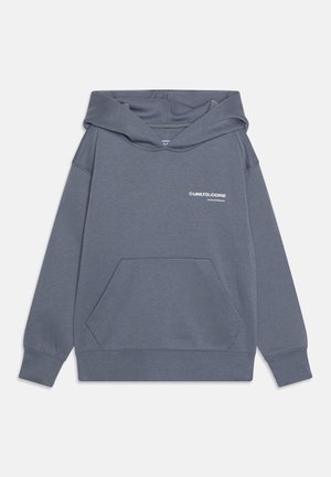 Grauer Kapuzenpullover aus weichem Stoff, mit einer Fronttasche, gerippten Bündchen und einem kleinen weißen Logo auf der linken Brustseite.