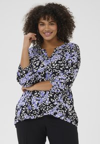 Schwarze Bluse mit lila und weißen Leopardenmuster, V-Ausschnitt und Dreiviertelärmeln. Weicher Stoff mit fließendem Design.