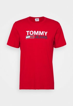 Rotes Baumwoll-T-Shirt mit kurzen Ärmeln, das "TOMMY" in Weiß und "JEANS" in Grau über einem Logo mit einem blauen, roten und weißen Design zeigt.