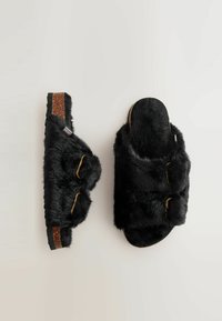 Sorte faux fur sandaler med dobbeljusterbare stropper, hardware i gyldent tone, struktureret kork sål og blødt polstring for komfort.