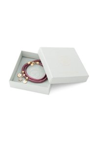 Paved bracelet in deep burgundy leather, featuring gold-colored accents and pendants in various shapes, presented in a light gray box.