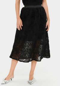 Faldă midi neagră, cu un model texturat de trandafiri, dintr-un material semi-transparent, și talie strânsă cu un band elastic neted. Asortată cu pantofi argintii.