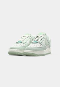 Jasnozielone sneakersy wykonane z zamszu i skóry, z białymi akcentami, perforowanym przodem, grubszą podeszwą oraz metką marki w odcieniu teal.
