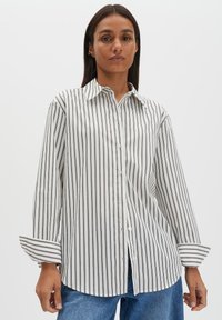 Weißes Hemd mit Knopfleiste, dünnen schwarzen vertikalen Streifen, langen Ärmeln und spitzem Kragen, aus glattem Stoff mit lockerem Schnitt.