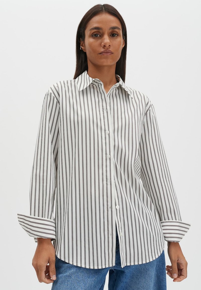 Weißes Hemd mit Knopfleiste, dünnen schwarzen vertikalen Streifen, langen Ärmeln und spitzem Kragen, aus glattem Stoff mit lockerem Schnitt.