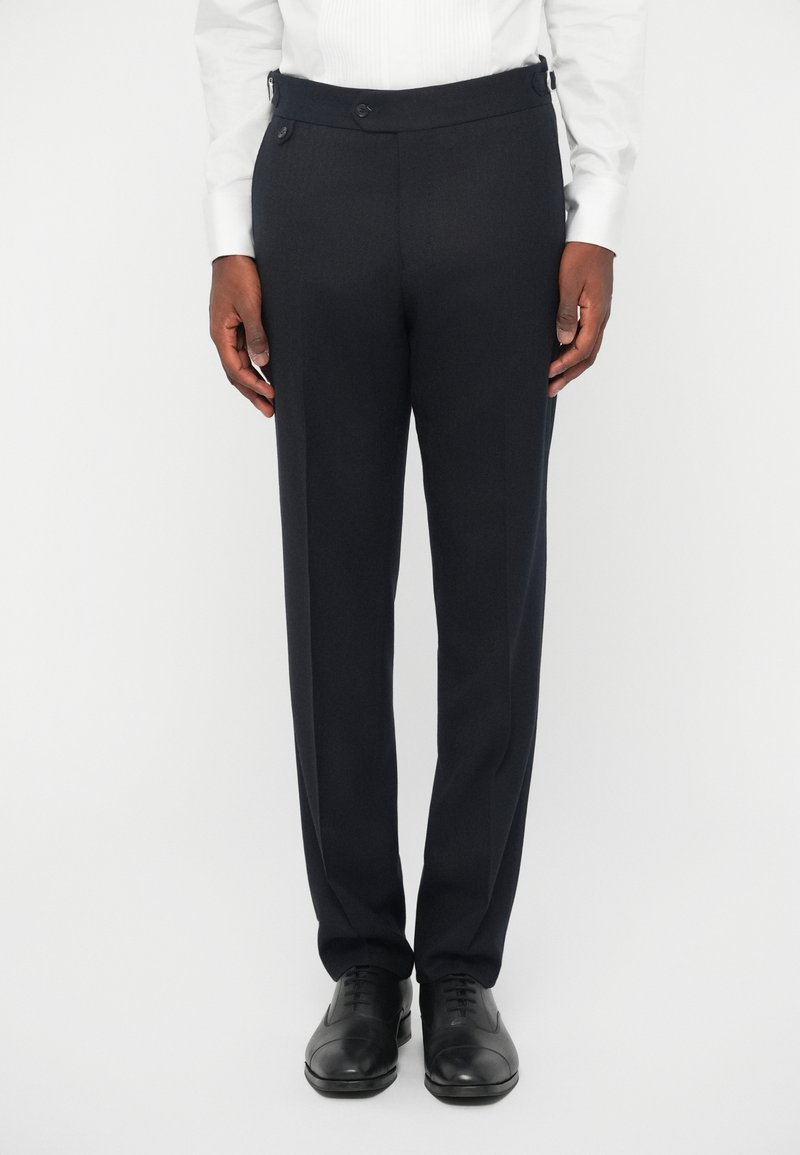 Tengerészekkel, sima textúrával, lapos fronttal, két oldalsó zsebbel, dupla gombos záródással és övbútorokkal ellátott nadrág, fekete cipővel párosítva.