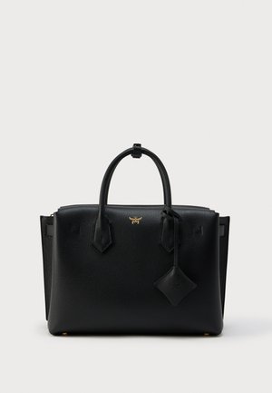 Black textured leather handbag with double handles, gold logo detail, and a leather tag hanging from one handle against a plain background.