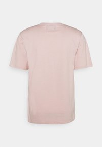 Tričko s krátkým rukávem z měkkého růžového bavlněného materiálu, s kulatým výstřihem a jednoduchým designem bez viditelných štítků nebo doplňků na zadní straně.