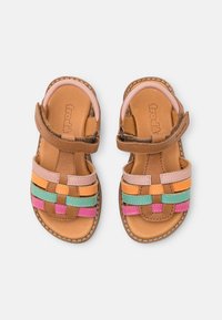 Sandalias de cuero marrón con tiras tejidas en colores rosa, naranja, verde y azul. Correa ajustable con cierre de velcro para un ajuste seguro.