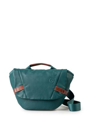 Turquoise crossbodytas met bruine leren accenten, een bovenhandvat en een verstelbare turquoise stoffen schouderriem op een witte achtergrond.