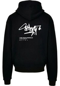 Črna kapuca z velikim belim grafičnim motivom na hrbtu, ki vsebuje stilizirano besedilo in logo. Pleteni manšeti in spodnji rob zagotavljajo prilegajoč zaključek.