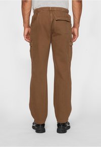 Bruine cargobroek met een elastische tailleband, twee zijzakken en één achterzak. Glad katoenen stof met een ontspannen pasvorm.