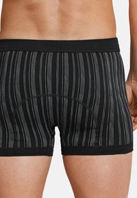 Boxer neri a righe, realizzati in tessuto morbido, con un design aderente, una fascia elastica liscia e sottili righe bianche a contrasto.