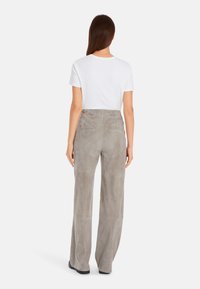 Grau Wildleder weite Beinhosen mit flacher Vorderseite, dezenten Taschen und glatter Textur, kombiniert mit einem schlichten weißen T-Shirt.