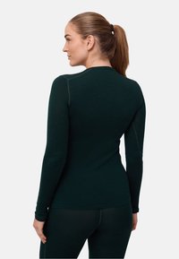 Tmavě zelený přiléhavý top s dlouhým rukávem vyrobený z měkké látky. Má ploché švy a kulatý výstřih, s hladkou texturou a štíhlým střihem.
