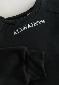Sweatshirt noir avec des poignets et un col côtelés, avec "ALLSAINTS" brodé en blanc sur la poitrine. Tissu doux et texturé.