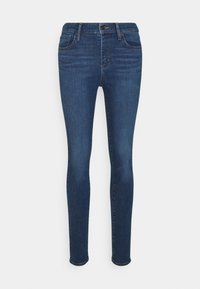 Jeans skinny de denim azul con cinco bolsillos, cremallera y un leve acabado descolorido. La tela presenta una textura suave y un cosido clásico.
