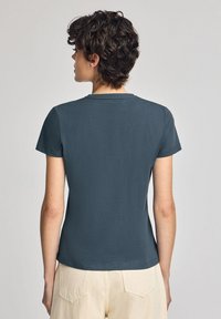 Donkerblauwe katoenen T-shirt met korte mouwen en een ronde hals. Gladde textuur, aansluitend ontwerp en een eenvoudige achterkant zonder zichtbare patronen of accenten.